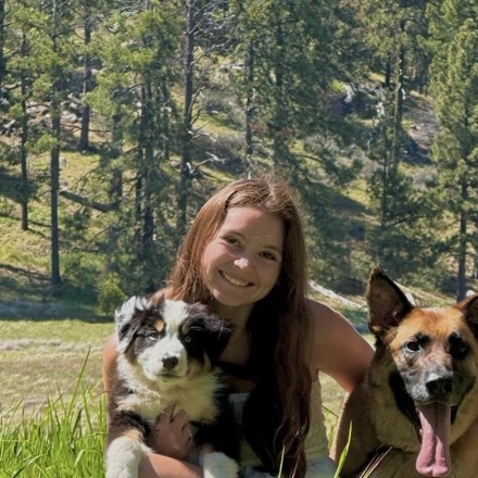 Victoria with two dogs in a sunny meadow.